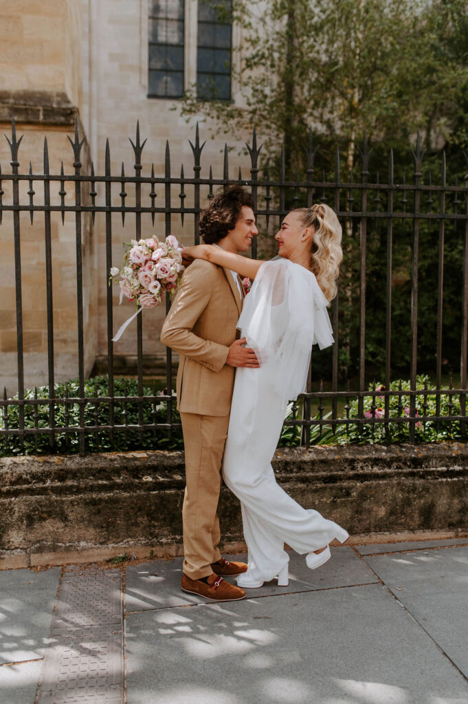Photo de couple, couple, costume beige, fleurs, rose, combinaison, robe de mariée, mariée, marié, cape, mariage civil, tenue de civile, coiffure de mariée, mariage