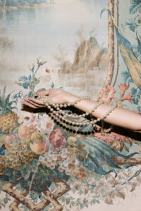 collier de perles, tapis fleuri, main de la mariée