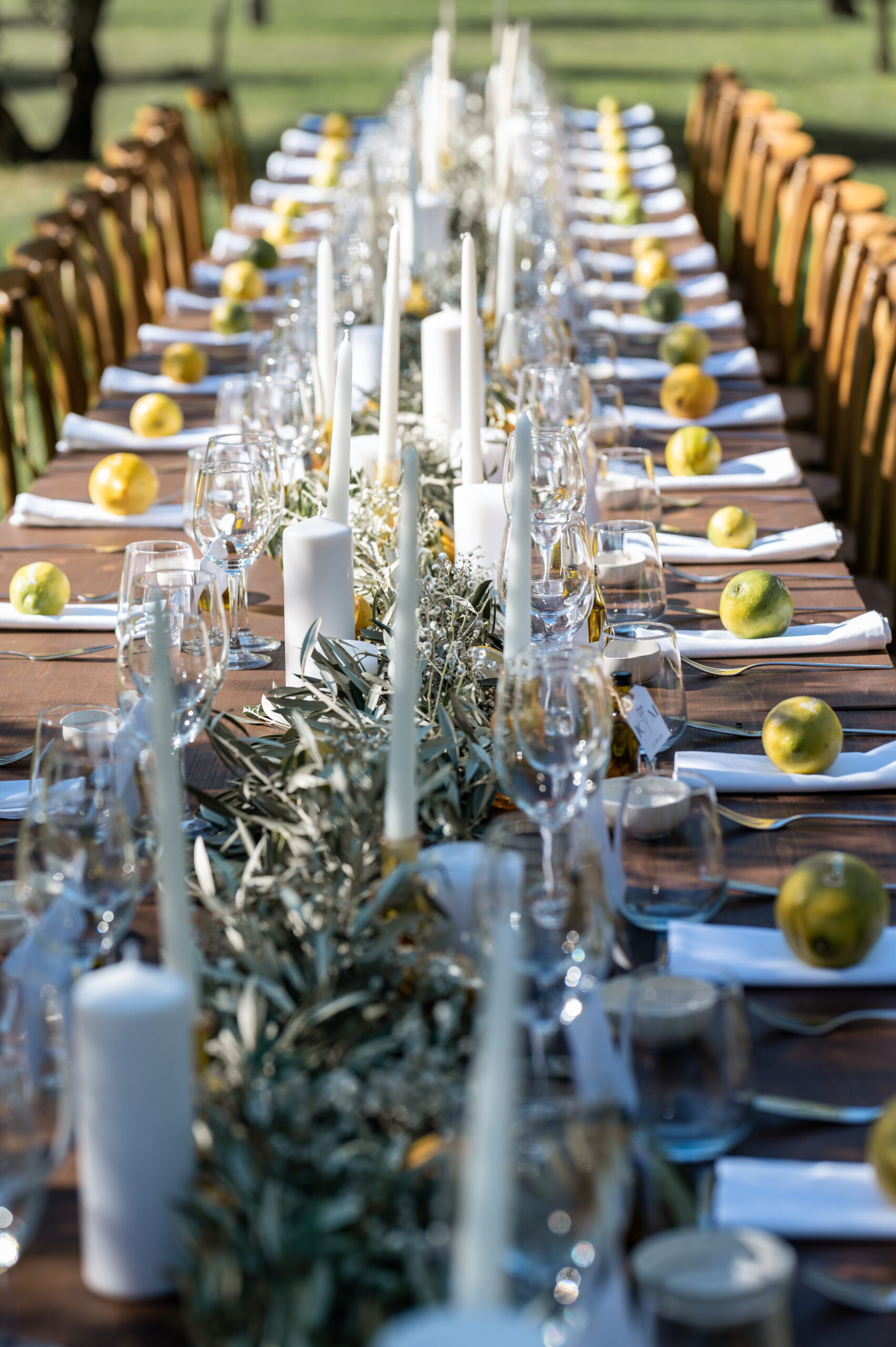 art de la table d'une longue table en bois avec des citrons des brins d'olivier et des bougies blanches dolce vita